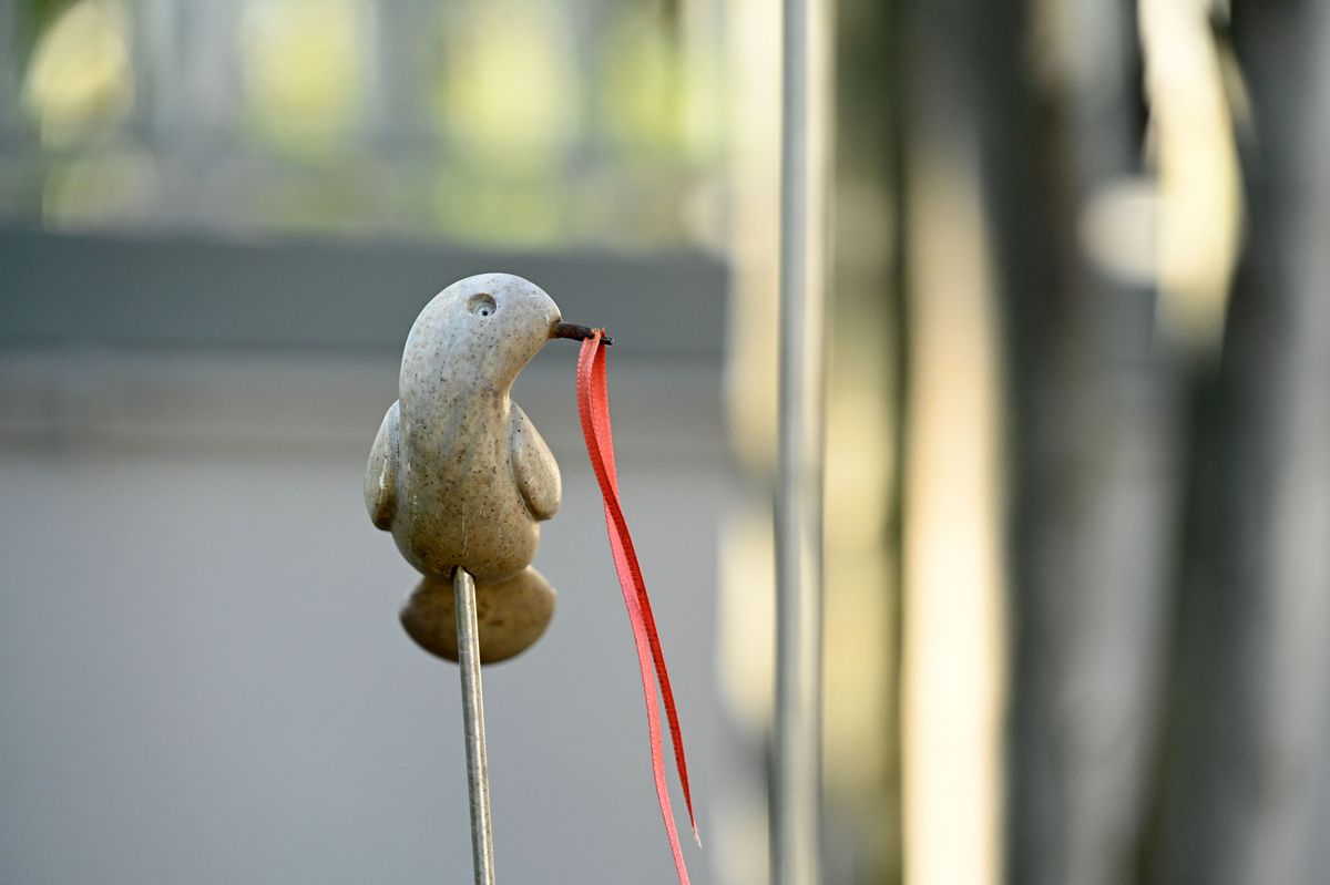 A small stone bird figurine with a red ribbon, softly lit.